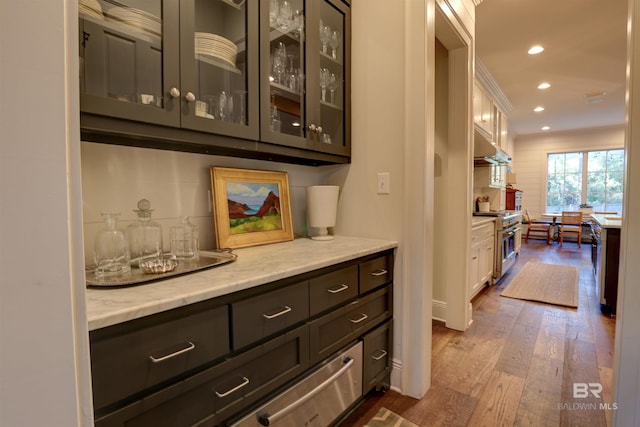 bar with under cabinet range hood, high end range, recessed lighting, and dark wood-style flooring