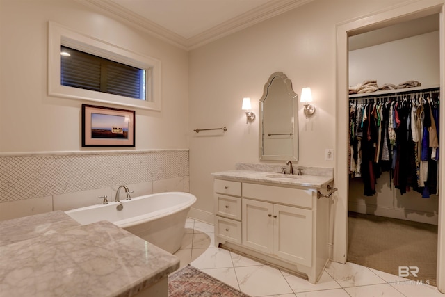 full bathroom with vanity, a freestanding tub, a spacious closet, crown molding, and marble finish floor