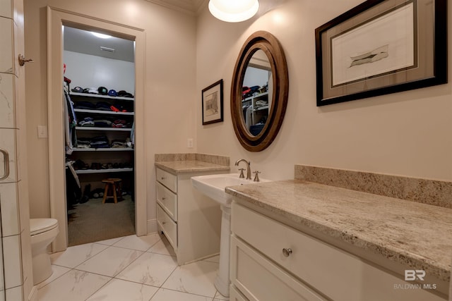 bathroom with marble finish floor, toilet, and a walk in closet