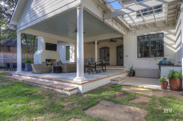 view of patio with an outdoor living space with a fireplace, a ceiling fan, and fence