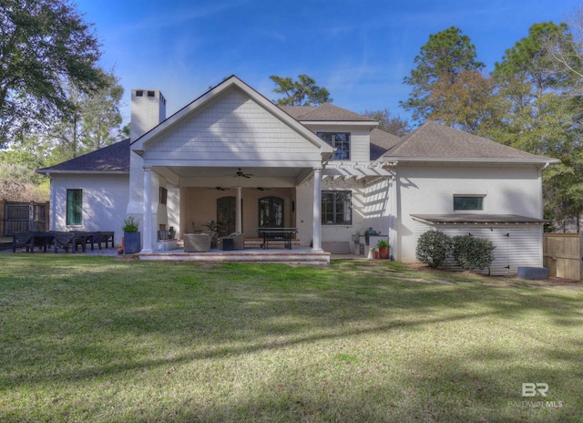 back of property with fence, a yard, a chimney, ceiling fan, and a patio area