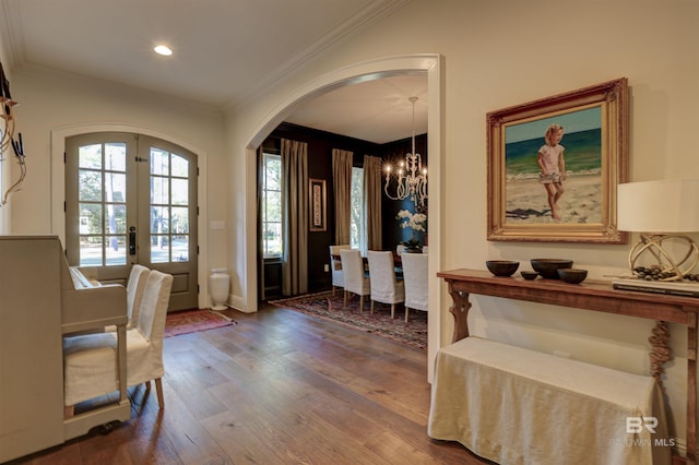 entryway with crown molding, a chandelier, french doors, wood finished floors, and arched walkways