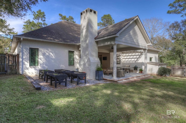 back of property with brick siding, a lawn, a patio, and fence