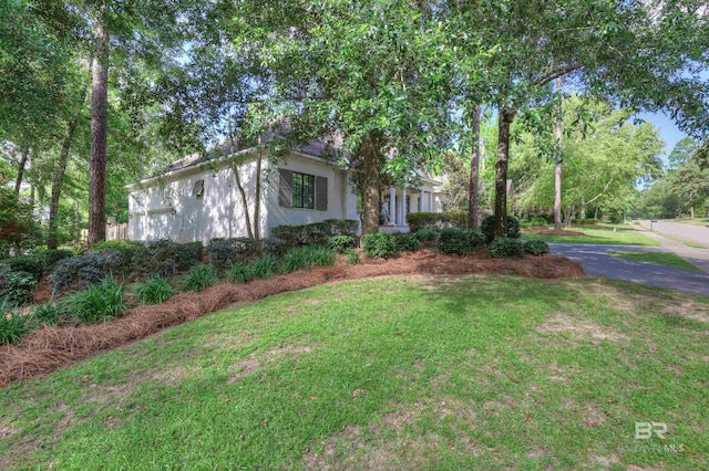 view of front of house with aphalt driveway, stucco siding, and a front lawn