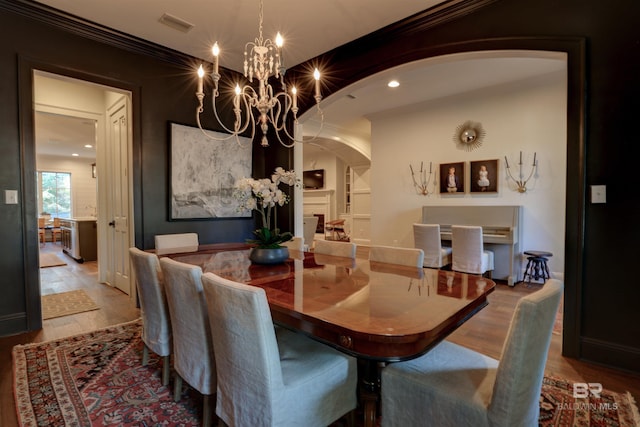 dining area featuring visible vents, wood finished floors, arched walkways, and ornamental molding