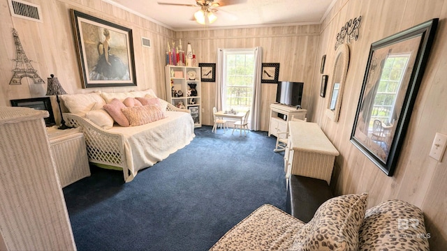 carpeted bedroom with wood walls, ceiling fan, and ornamental molding