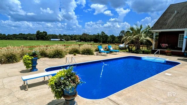 view of swimming pool with a patio area and a diving board