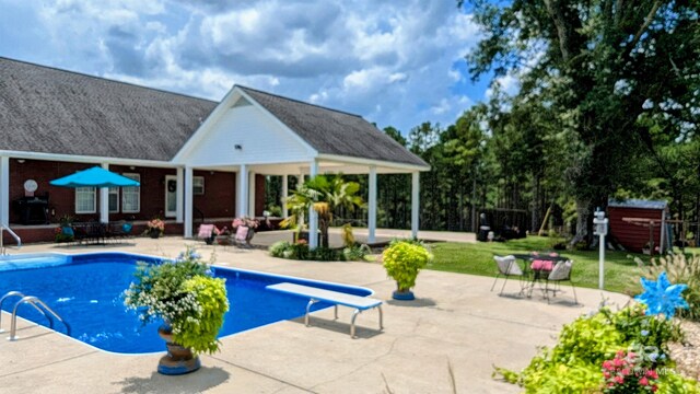 view of pool with a patio and a diving board