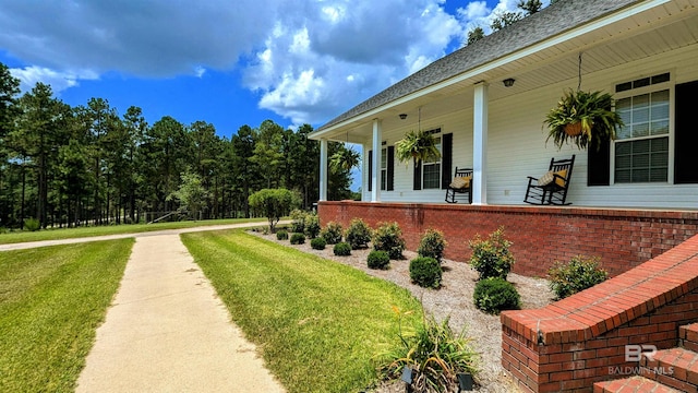 view of side of property with covered porch and a yard