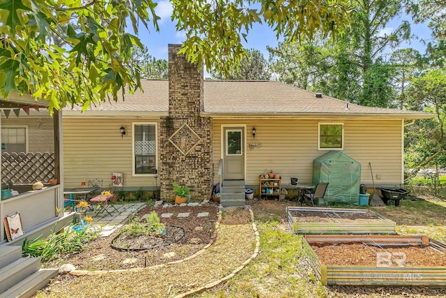 45 Caisson Trce, Spanish Fort, AL 36527 - back of house with a vegetable garden, entry steps, a chimney, a patio, and roof with shingles