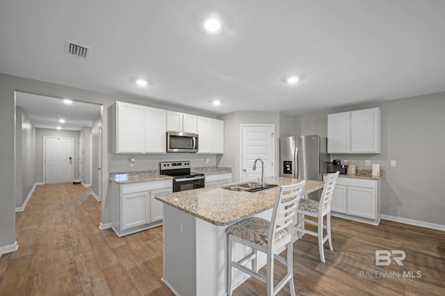 17208 Muse St, Loxley, AL 36551 - kitchen with appliances with stainless steel finishes, a sink, baseboards, wood finished floors, and a breakfast bar