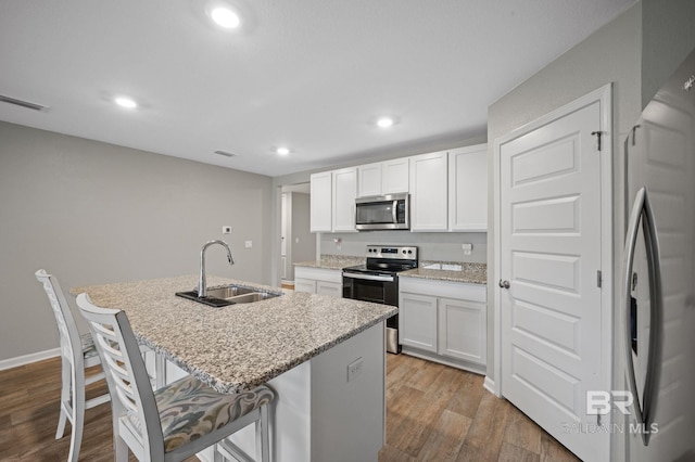 17208 Muse St, Loxley, AL 36551 - kitchen with appliances with stainless steel finishes, a sink, wood finished floors, a kitchen bar, and a center island with sink