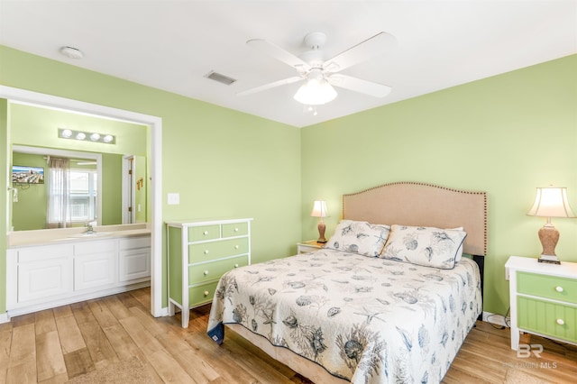 bedroom with light wood-type flooring, visible vents, a sink, and ceiling fan