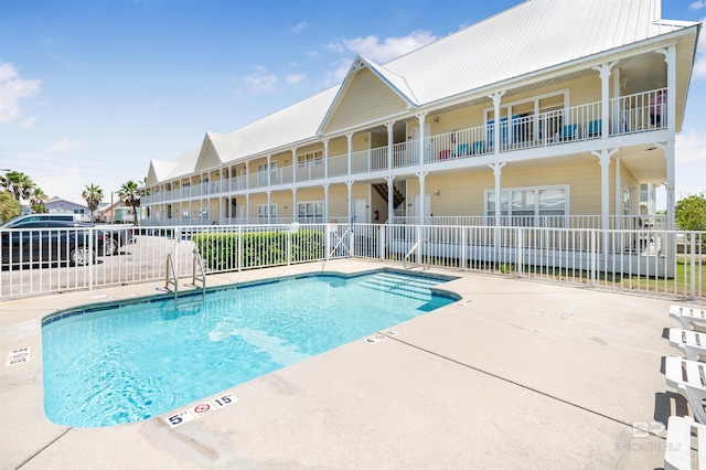 community pool with fence and a patio