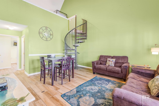 living area featuring a towering ceiling, stairs, baseboards, and wood finished floors