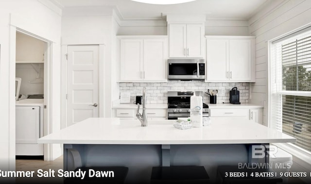 2760 Salt Dr, Orange Beach, AL 36561 - kitchen featuring white cabinets, a breakfast bar, backsplash, and appliances with stainless steel finishes