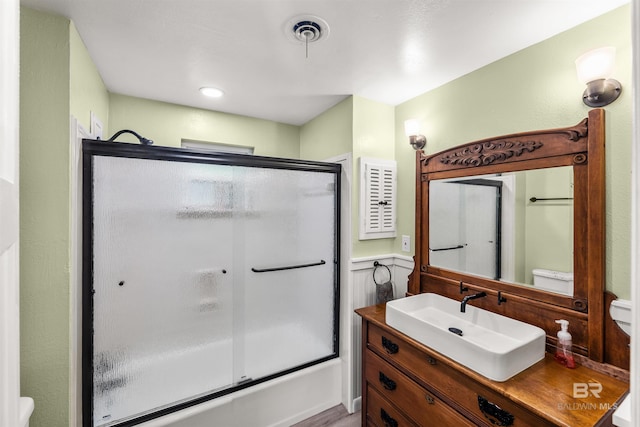 7410 Helton Dr, Foley, AL 36535 - bathroom with toilet, vanity, shower / bath combination with glass door, and wainscoting