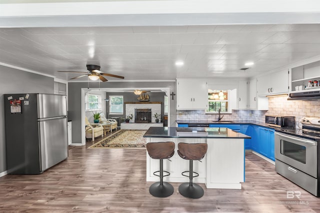 7410 Helton Dr, Foley, AL 36535 - kitchen with appliances with stainless steel finishes, a sink, blue cabinetry, healthy amount of natural light, and ornamental molding