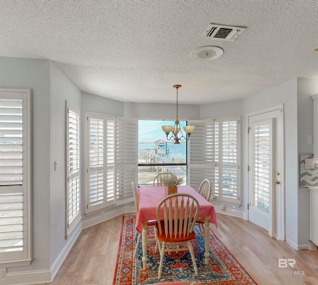 dining space with an inviting chandelier, light wood-style floors, visible vents, and baseboards