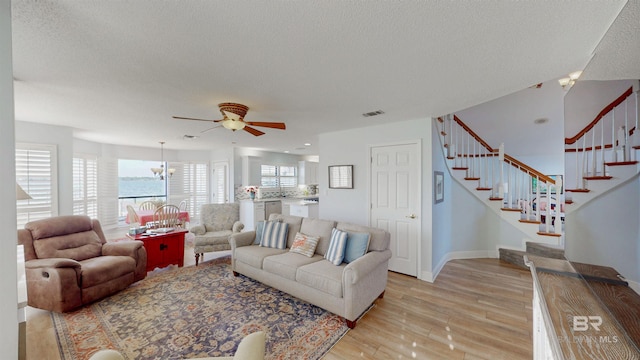 living room with stairway, a textured ceiling, and light wood finished floors