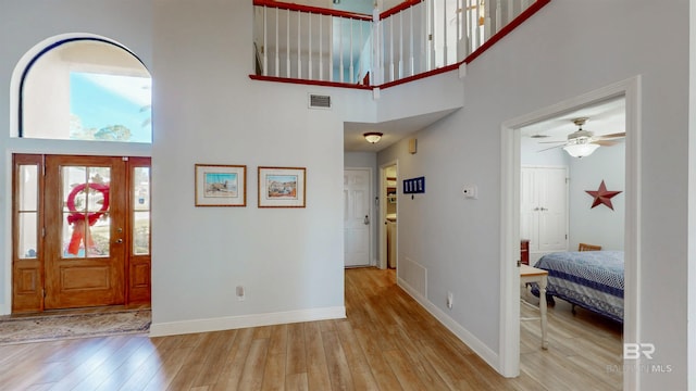 foyer featuring visible vents, a towering ceiling, baseboards, and hardwood / wood-style flooring