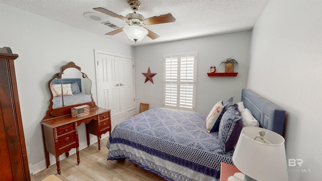 bedroom featuring wood finished floors, visible vents, ceiling fan, a closet, and a textured ceiling