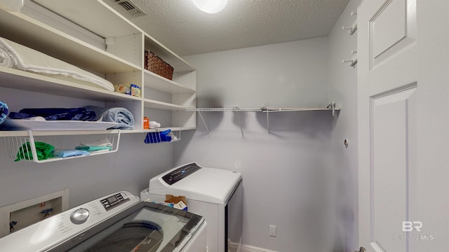 clothes washing area with laundry area, a textured ceiling, visible vents, and separate washer and dryer