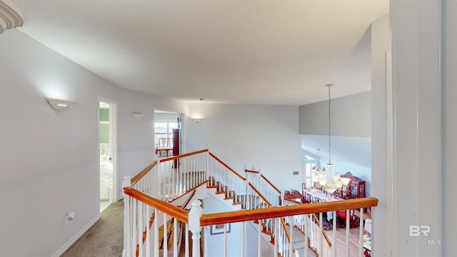 stairway featuring an inviting chandelier, baseboards, carpet, and vaulted ceiling