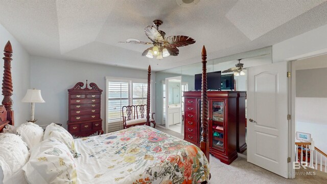 bedroom with light carpet, a textured ceiling, and a raised ceiling