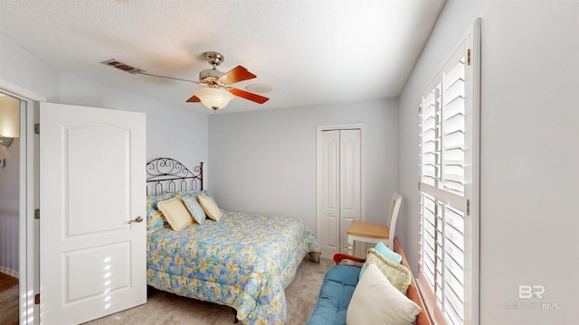 bedroom with a closet, a textured ceiling, visible vents, and a ceiling fan