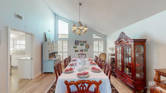 dining room featuring a chandelier, visible vents, high vaulted ceiling, and light wood-style floors