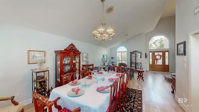 dining room with baseboards, high vaulted ceiling, an inviting chandelier, and light wood finished floors