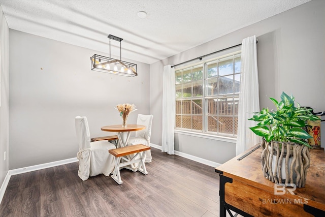 dining space featuring dark wood-type flooring and a textured ceiling