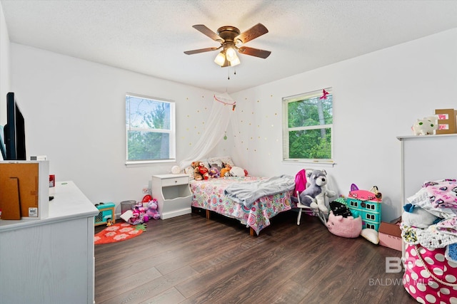 bedroom with ceiling fan, dark hardwood / wood-style floors, and a textured ceiling