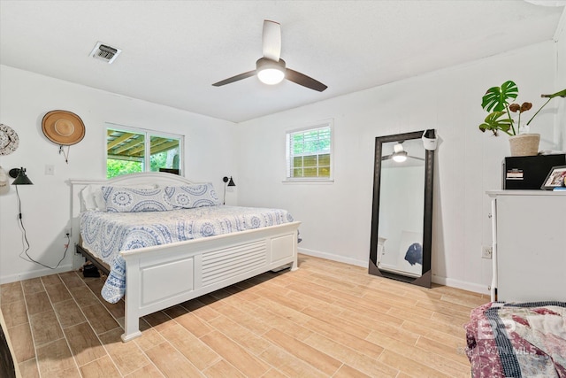 bedroom featuring ceiling fan, multiple windows, and light wood-type flooring