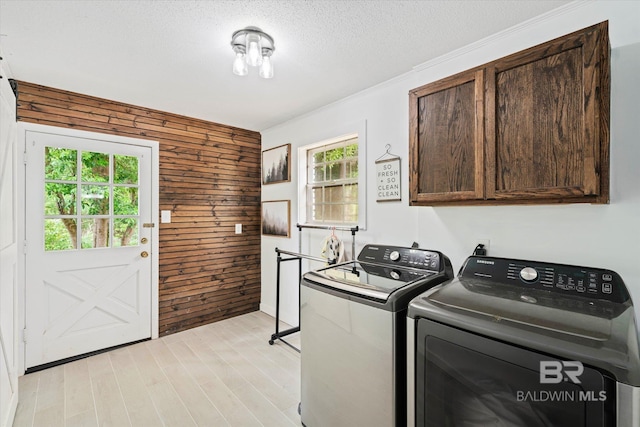 washroom featuring cabinets, separate washer and dryer, a textured ceiling, and wood walls