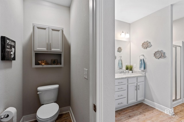 bathroom featuring hardwood / wood-style flooring, toilet, vanity, and a shower with shower door