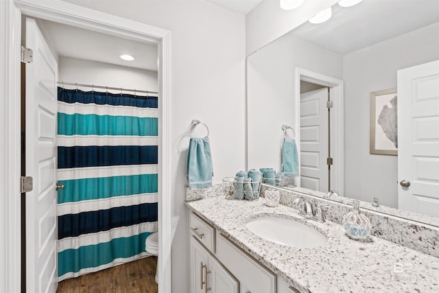 bathroom with wood-type flooring, toilet, vanity, and walk in shower