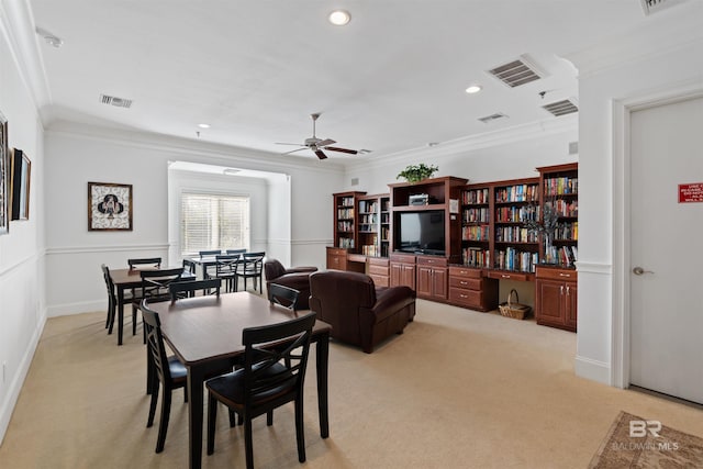 dining area featuring light carpet, ceiling fan, and crown molding