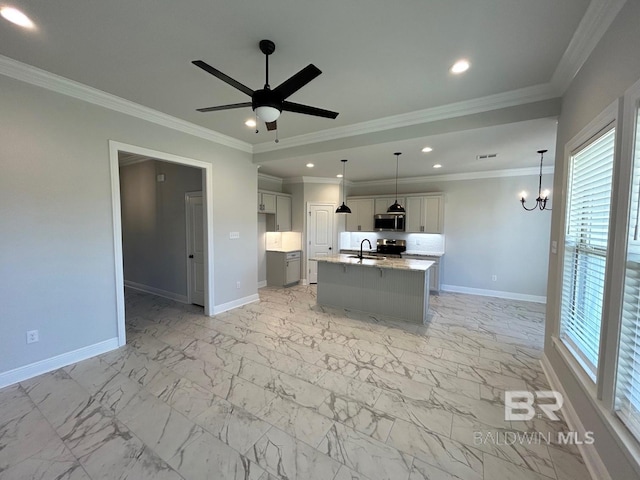 kitchen with decorative light fixtures, crown molding, light stone countertops, and a kitchen island with sink