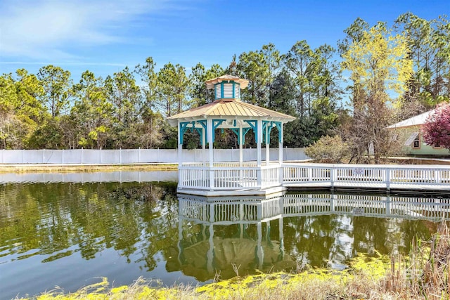 view of dock with a water view, fence, and a gazebo