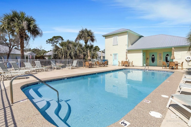 community pool with a patio area and fence