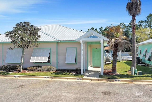 view of front of house featuring metal roof, a front yard, and central air condition unit