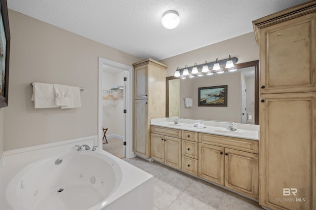 full bath with double vanity, a textured ceiling, a tub with jets, and a sink