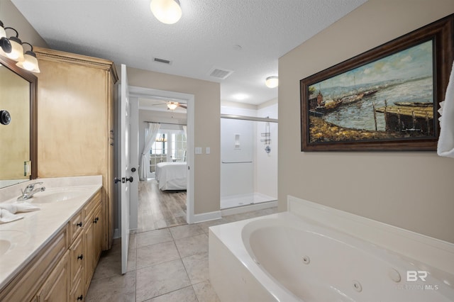 ensuite bathroom featuring visible vents, a stall shower, a sink, a textured ceiling, and ensuite bath