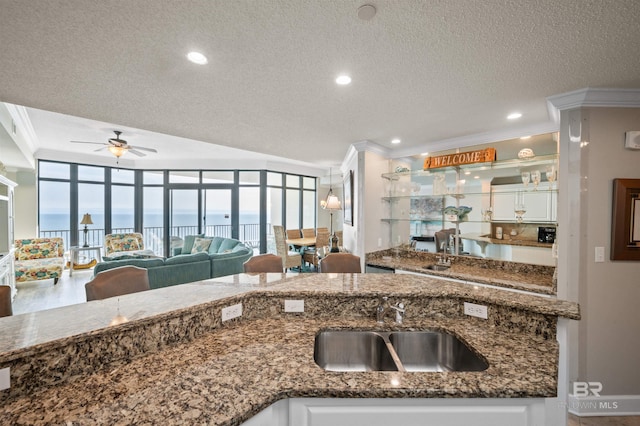 kitchen featuring a sink, dark stone countertops, white cabinetry, and crown molding