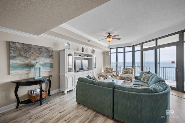 living room with ornamental molding, light wood-type flooring, visible vents, and a textured ceiling