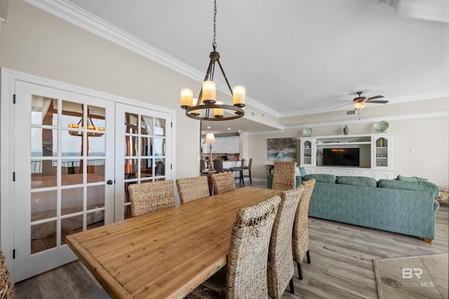 dining space with light wood-type flooring, french doors, crown molding, and ceiling fan with notable chandelier