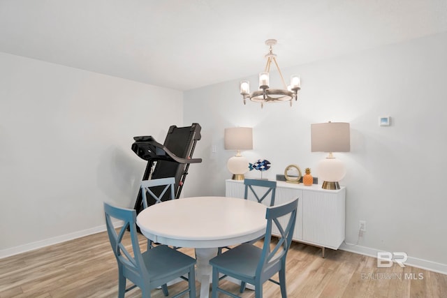 dining area featuring baseboards, a notable chandelier, and light wood finished floors