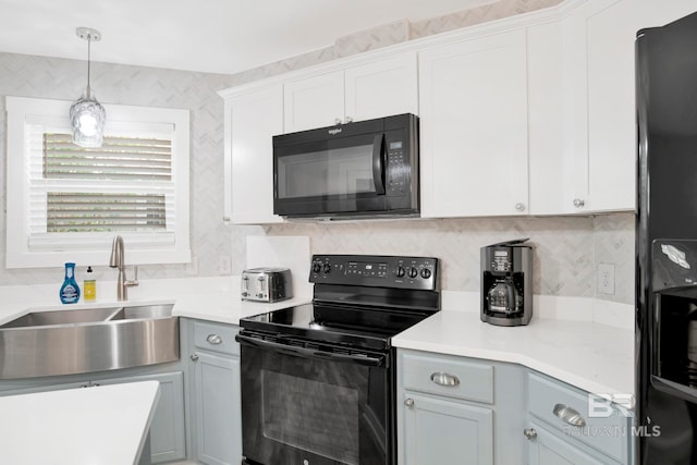 kitchen with decorative backsplash, a sink, light countertops, black appliances, and decorative light fixtures